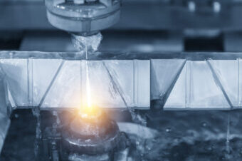 Close-up of the wire – EDM CNC machine while cutting the sample work pieces in light blue tone and lighting effect